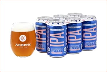 6-pack of blue 12oz cans of IPA with a 12oz stemeless glass of copper-colored west coast IPA over a white background